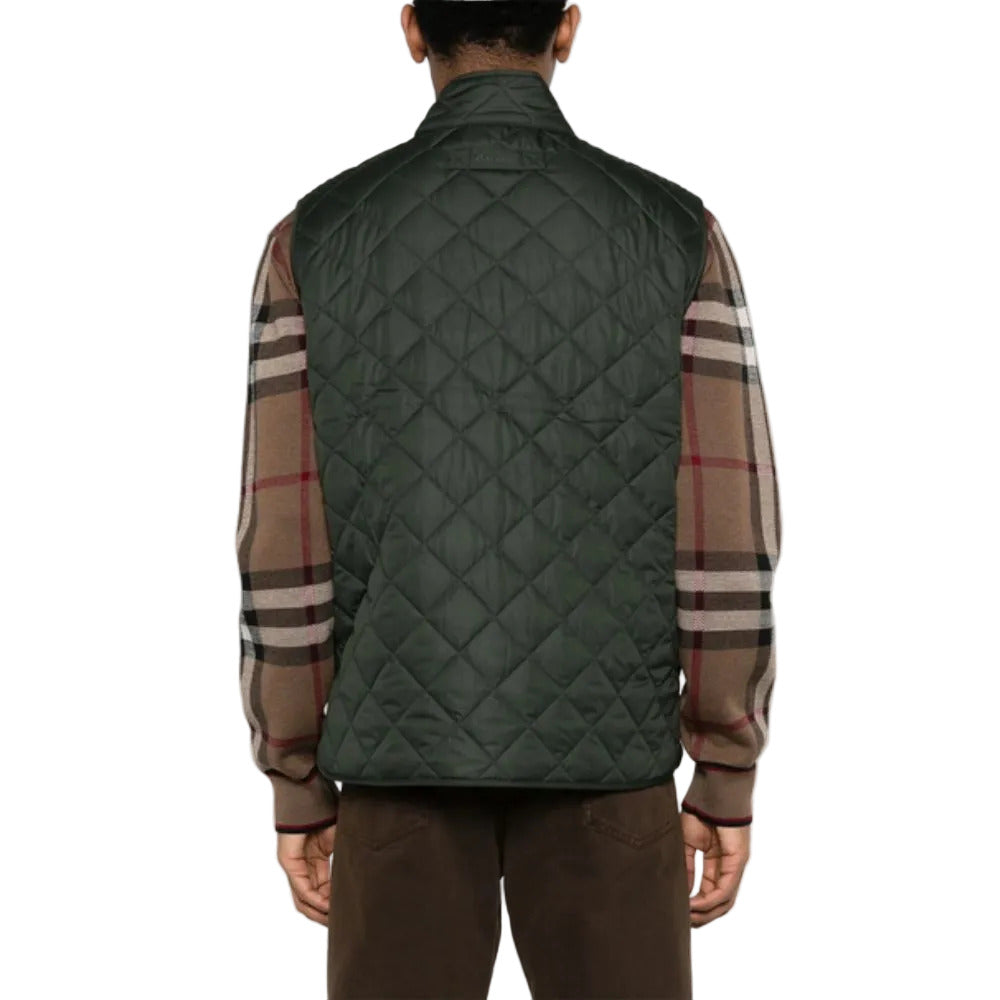 Person wearing a green quilted vest over a plaid shirt on a white background