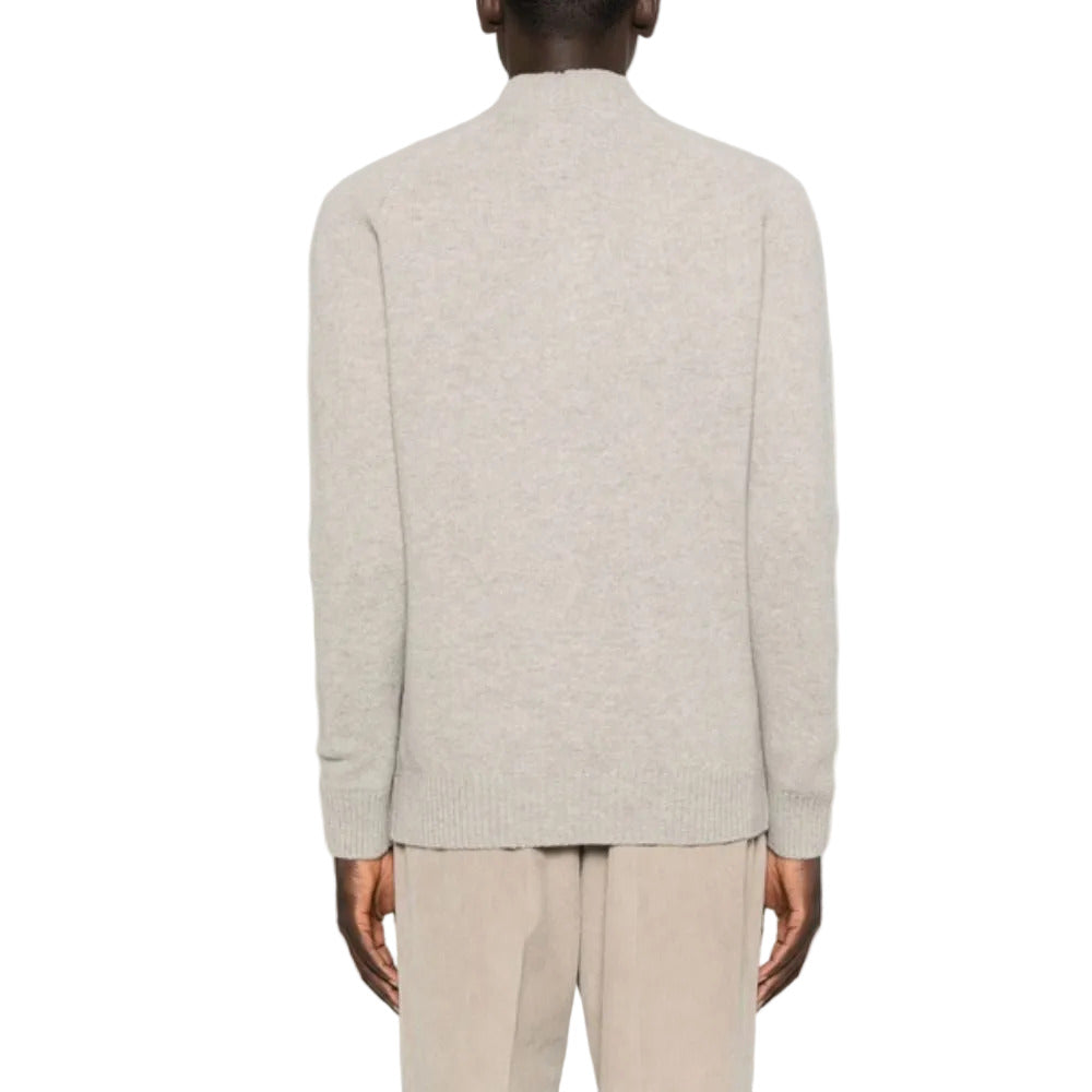 Person wearing a light gray sweater and beige pants on a white background