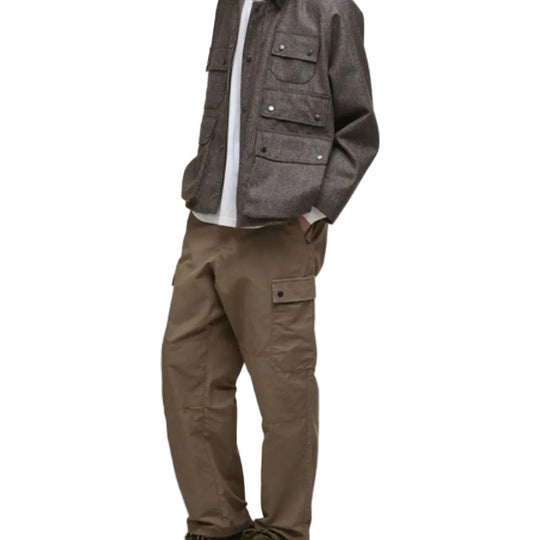 Person wearing a gray jacket and brown pants on a white background