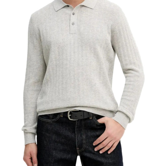 Person wearing a light gray long-sleeve polo shirt over a dark gray sweater with dark jeans on a white background.