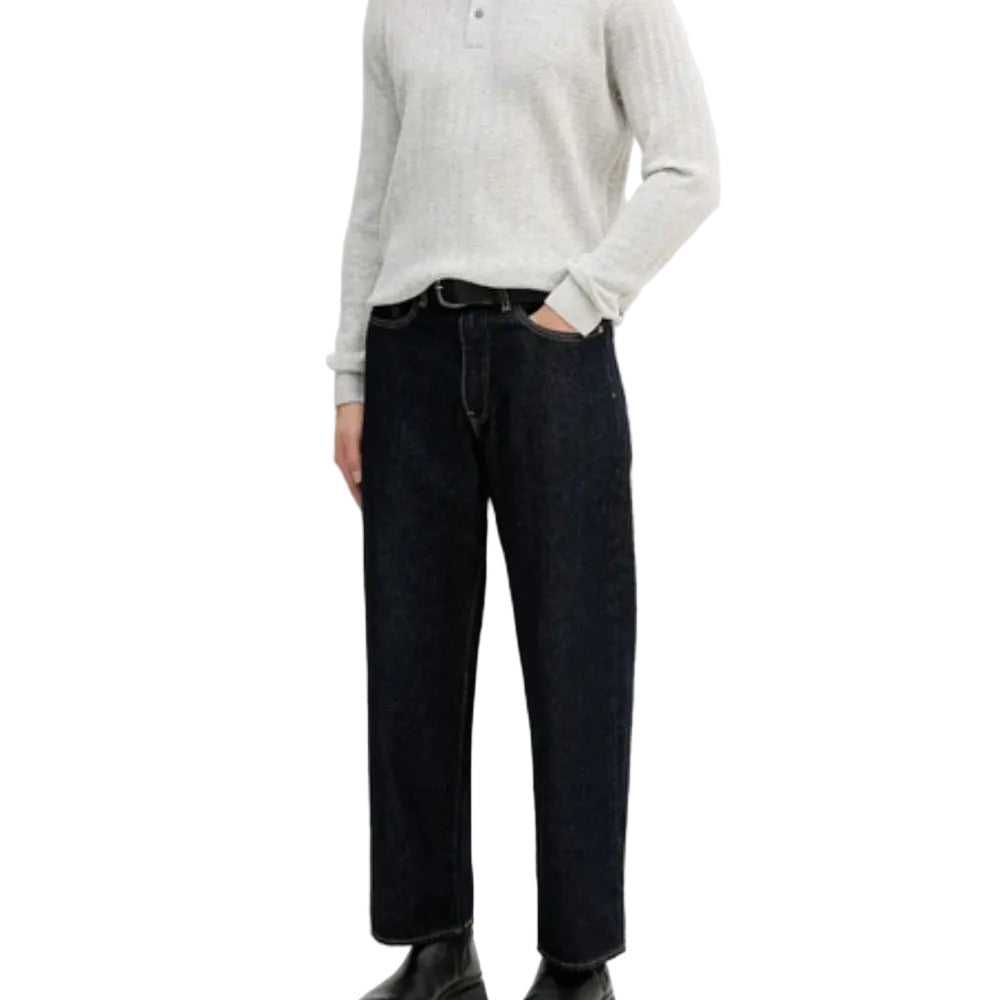 Person wearing a light gray sweater and dark blue jeans on a white background