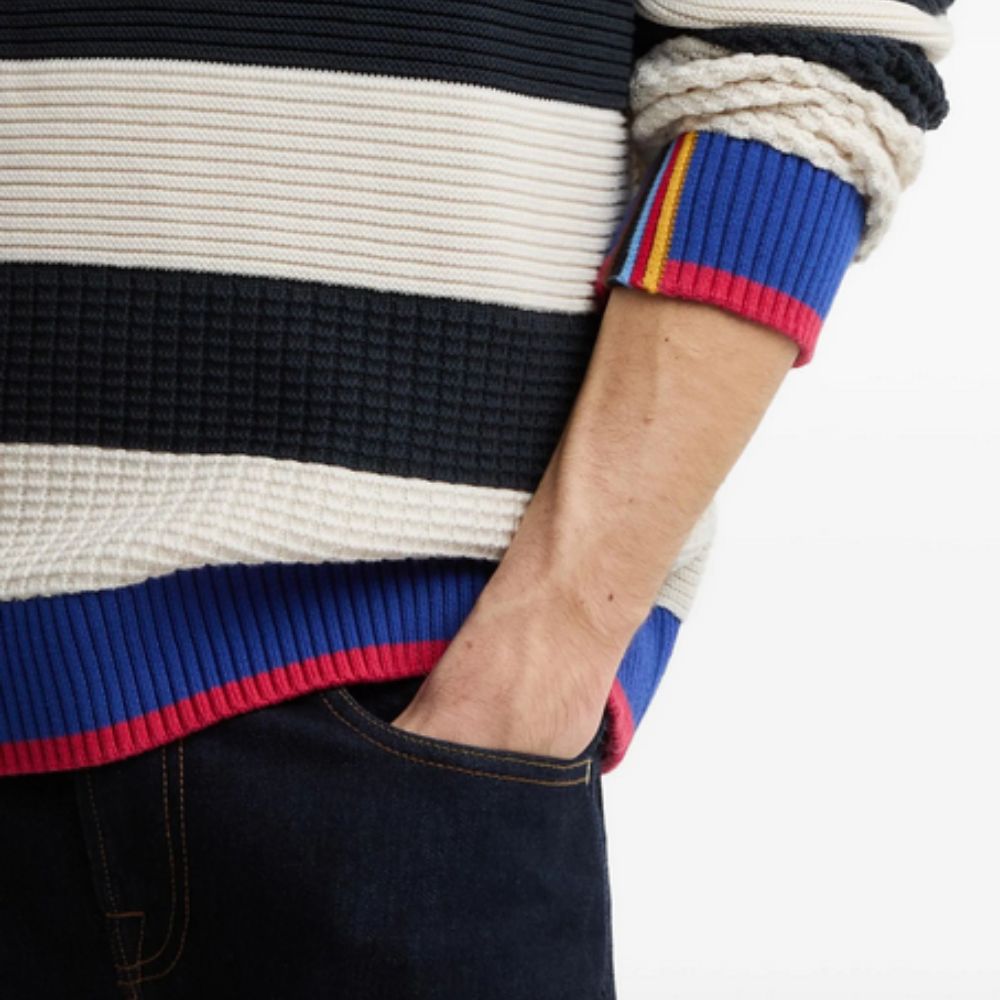 Close-up of a person wearing a BARBOUR X PAUL SMITH Relaxed Nautical-Style Sweater with colorful cuffs.