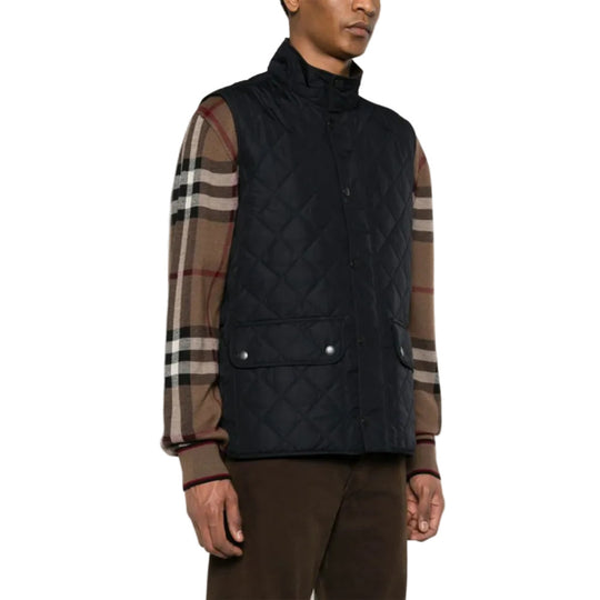 Man wearing a black quilted vest with plaid sleeves on a white background