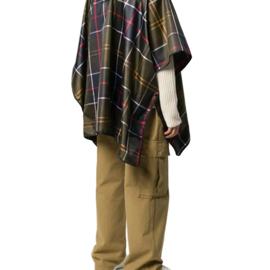 Person wearing a plaid poncho and beige pants on a white background