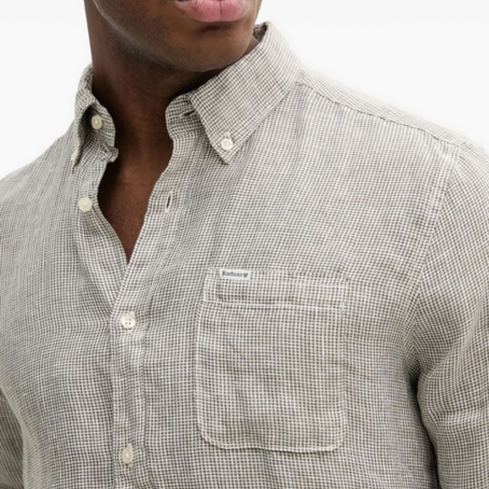 Close-up of a person wearing a checkered shirt with a brand logo on a white background