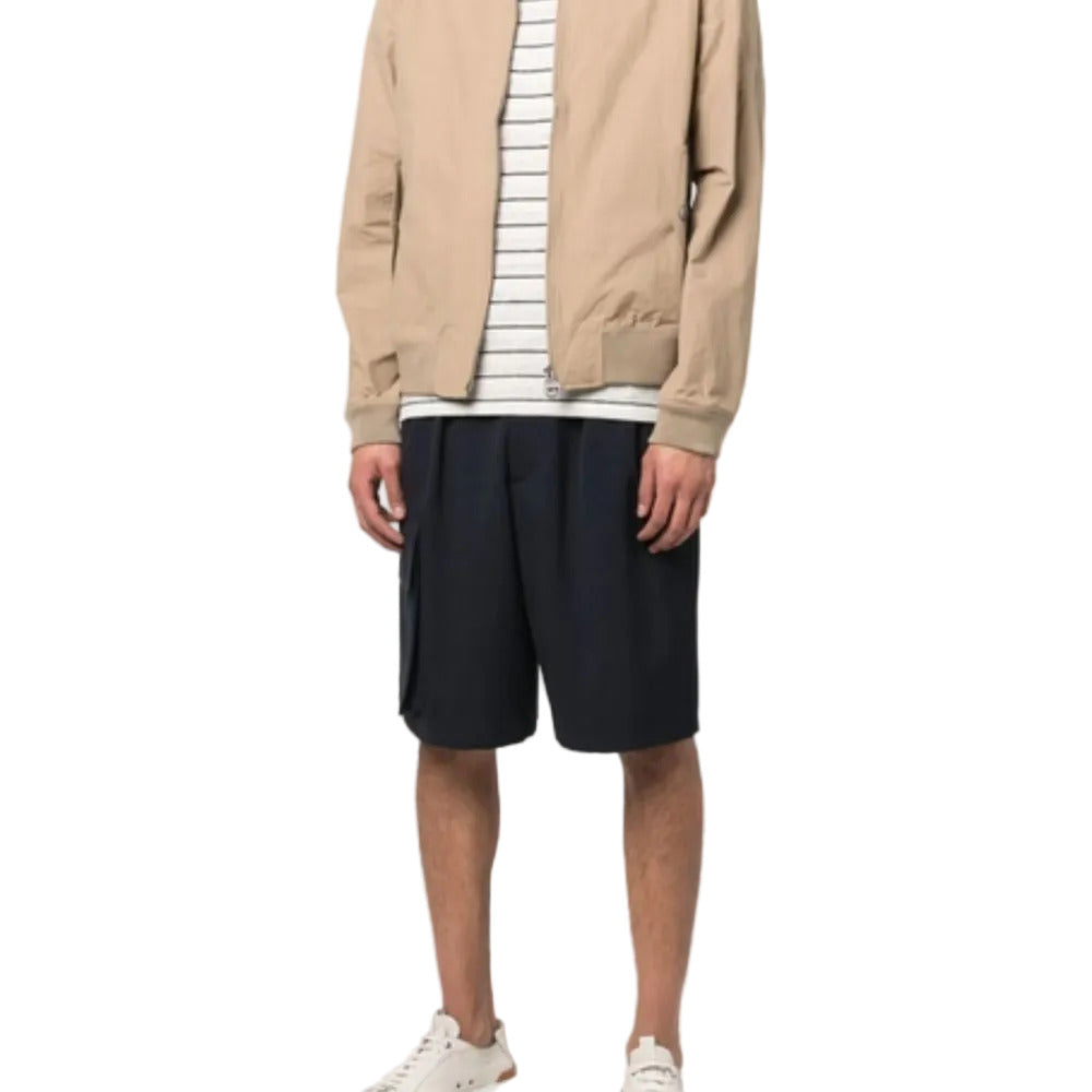 Person wearing a beige jacket, striped shirt, and black shorts on a white background