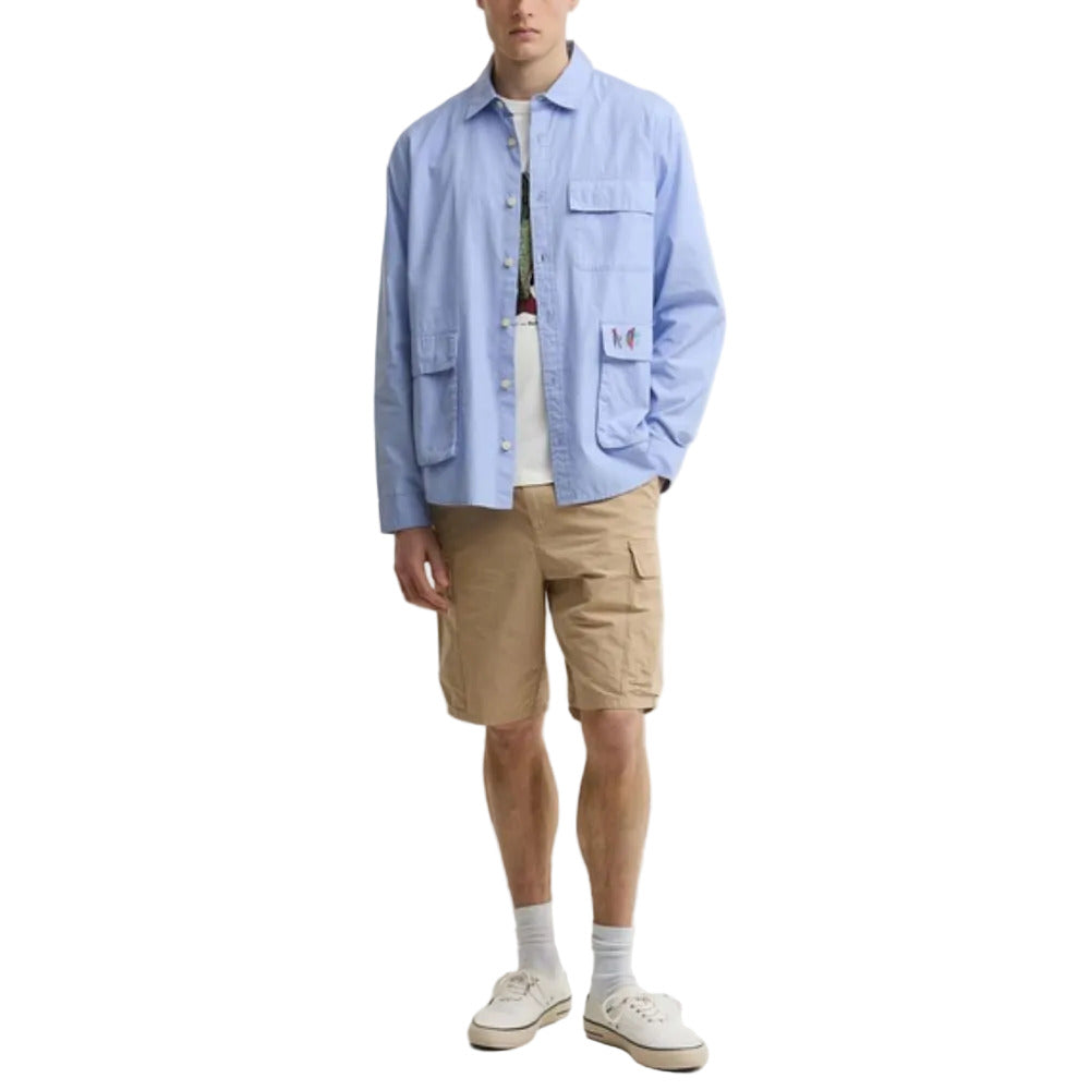 Person wearing a light blue shirt, beige shorts, and white sneakers on a white background