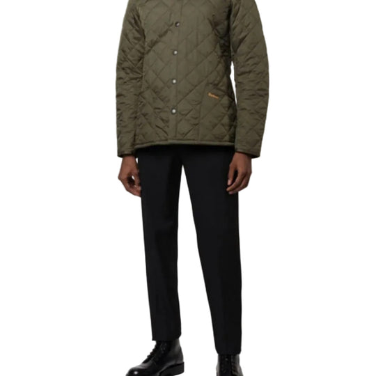 Person wearing a green quilted jacket and black pants on a white background