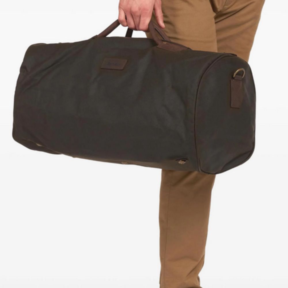 Person holding a large brown duffel bag against a white background
