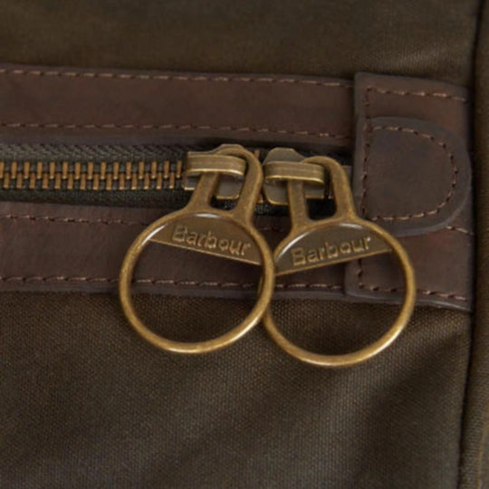Close-up of a brown leather bag with gold zipper pulls featuring the Barbour logo.
