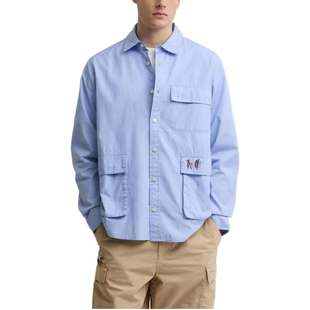 Person wearing a light blue shirt with two pockets on a white background