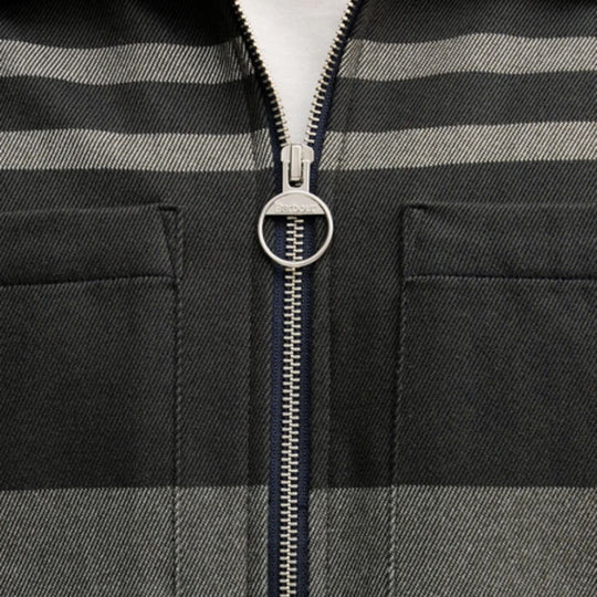 Close-up of a zipper on a black and gray striped jacket