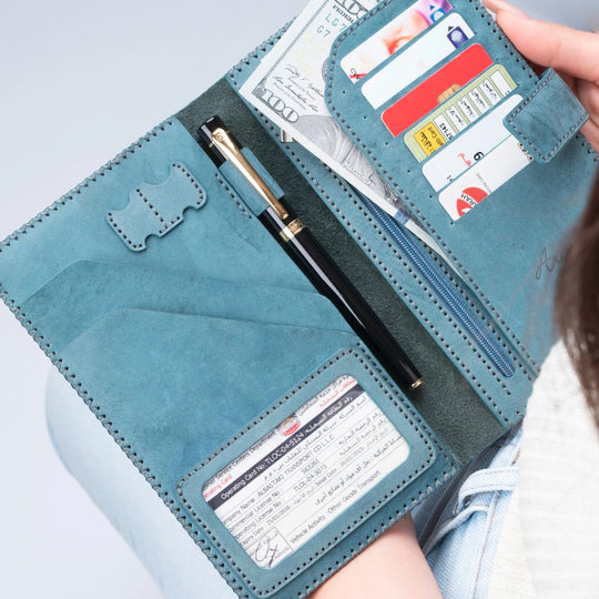 Open teal wallet with cards and a pen on a light blue background