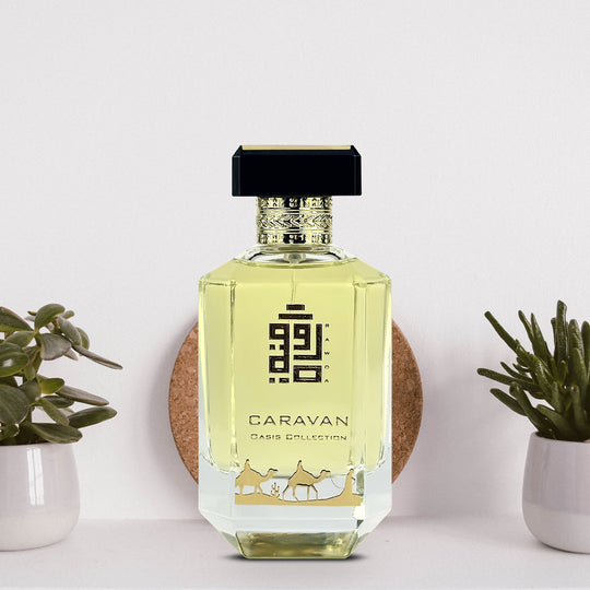 An EDP 100mL bottle of Caravan fragrance by Rawda kept on a white surface decorated with cactus plants