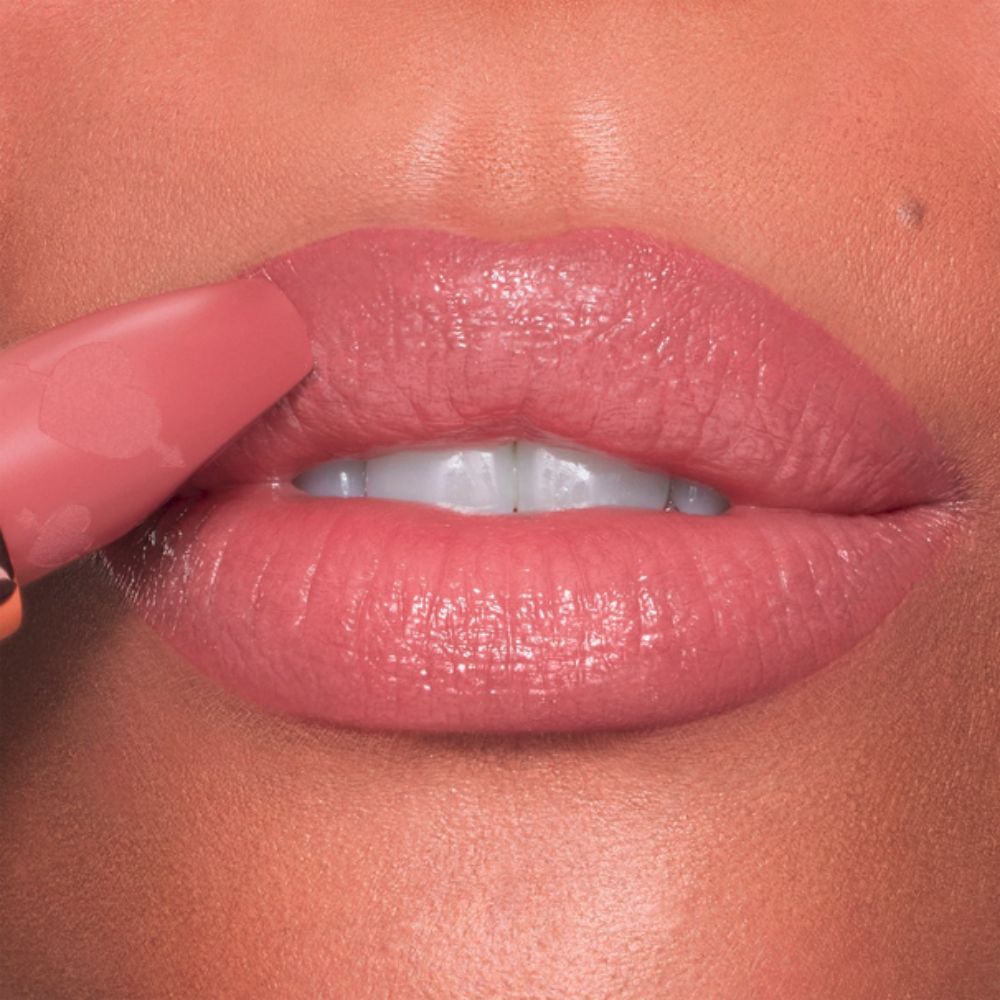 Close-up of lips being touched with a Charlotte Tilbury Pillow Talk Love Effect Lipstick Matte Revolution - Naughty Talk lipstick.