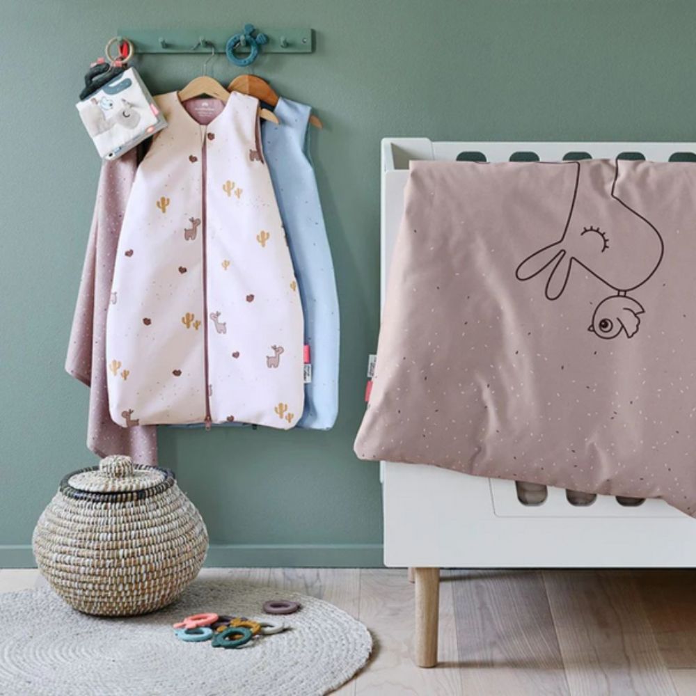 Children's room with Sleeping Bags, baby blankets, a crib, and toys on a green wall. 