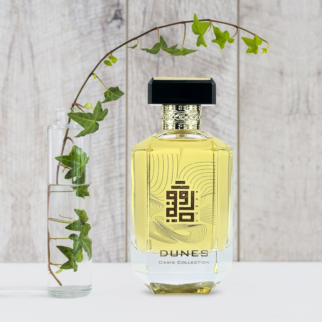 An EDP 100mL bottle of Dunes fragrance by Rawda kept besides a glass vase with water plant