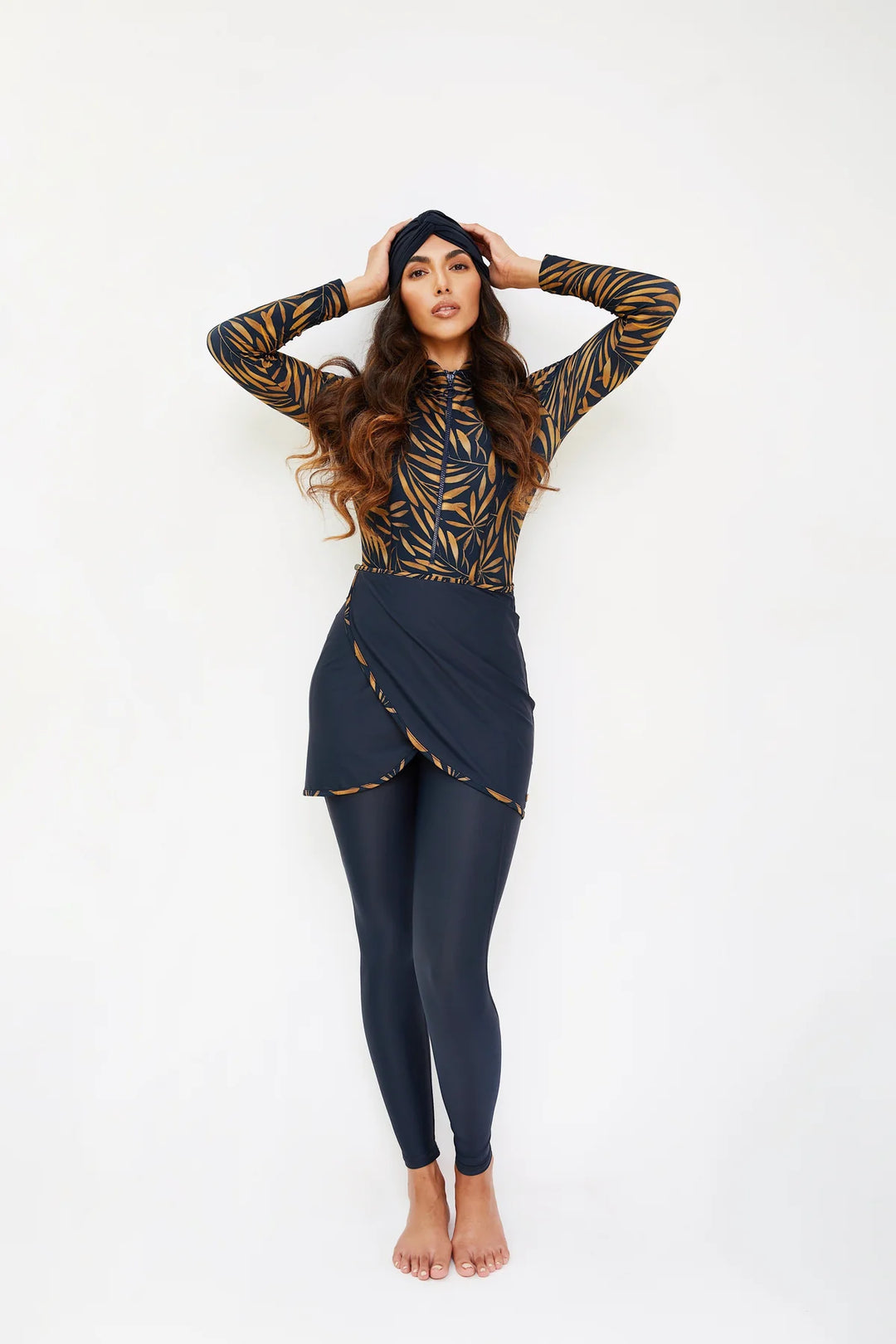 Model wearing a navy blue and gold leaf printed modest swimsuit with leggings and turban