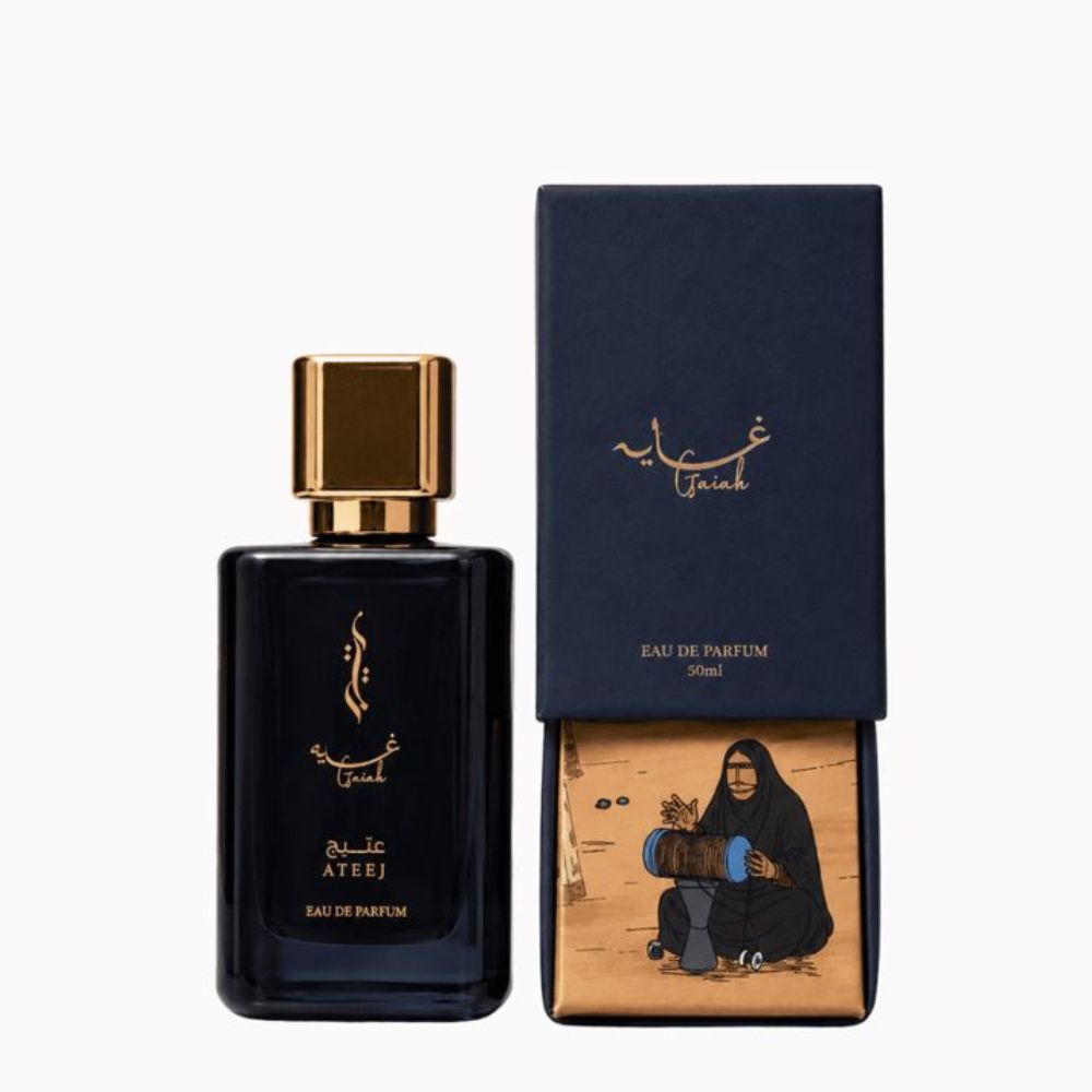 A bottle of Ateej Gaiah Eau de Parfum next to its box. The bottle is a deep navy blue with a metallic gold cap and gold lettering.