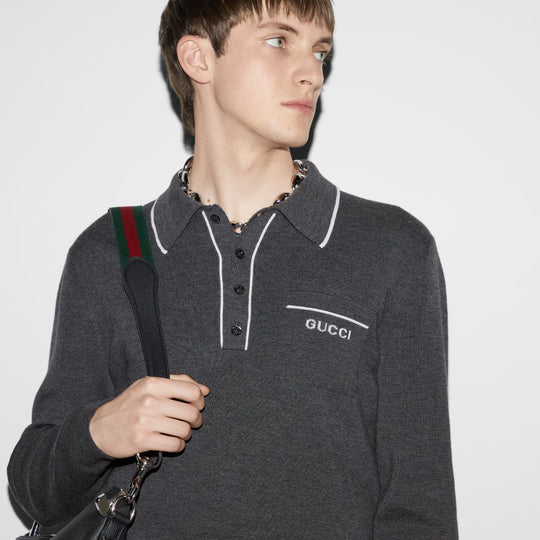 Model casually styled knitted polo shirt with a black satchel bag