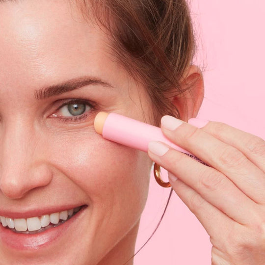A person applies PEACE OUT SKINCARE Retinol Eye Stick under their eye, smiling