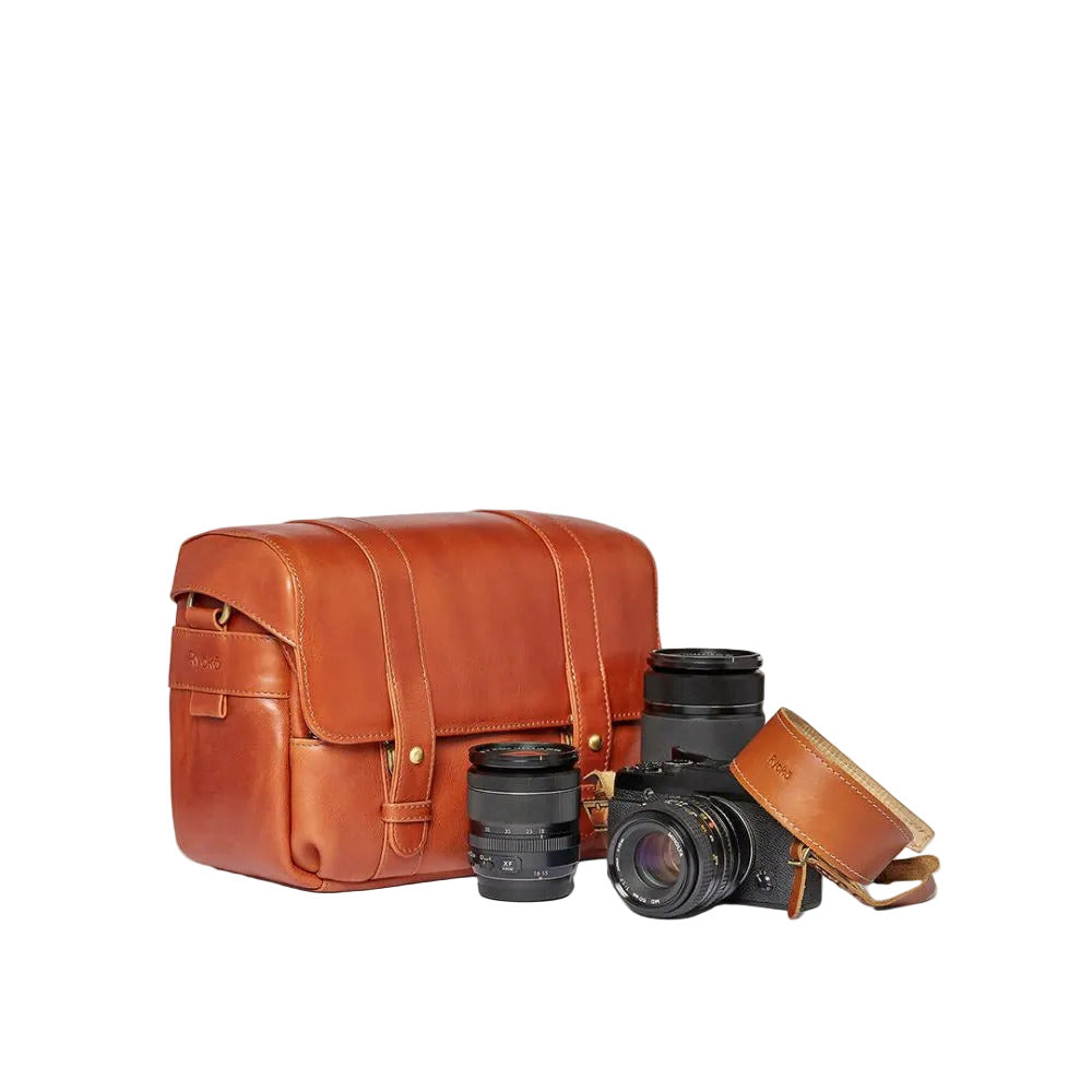 Brown leather camera bag with a camera and lenses on a white background