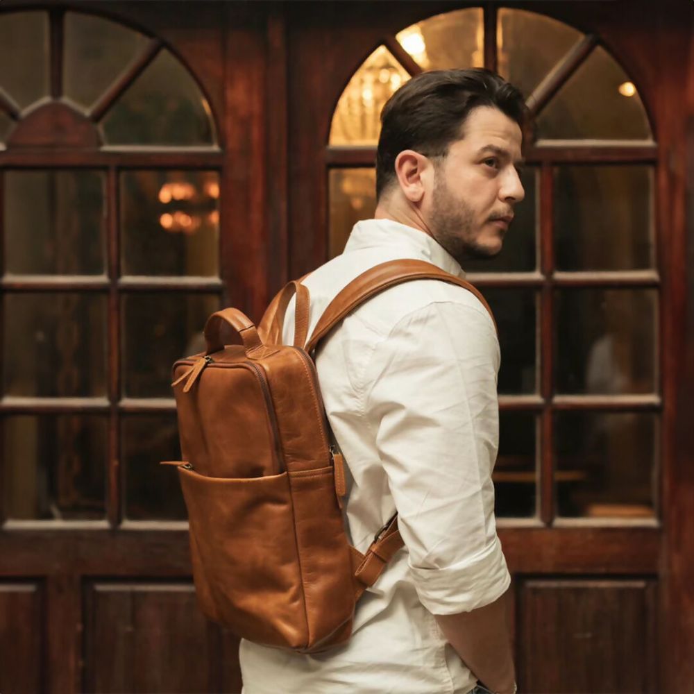 Man wearing a brown leather backpack in front of a wooden door.