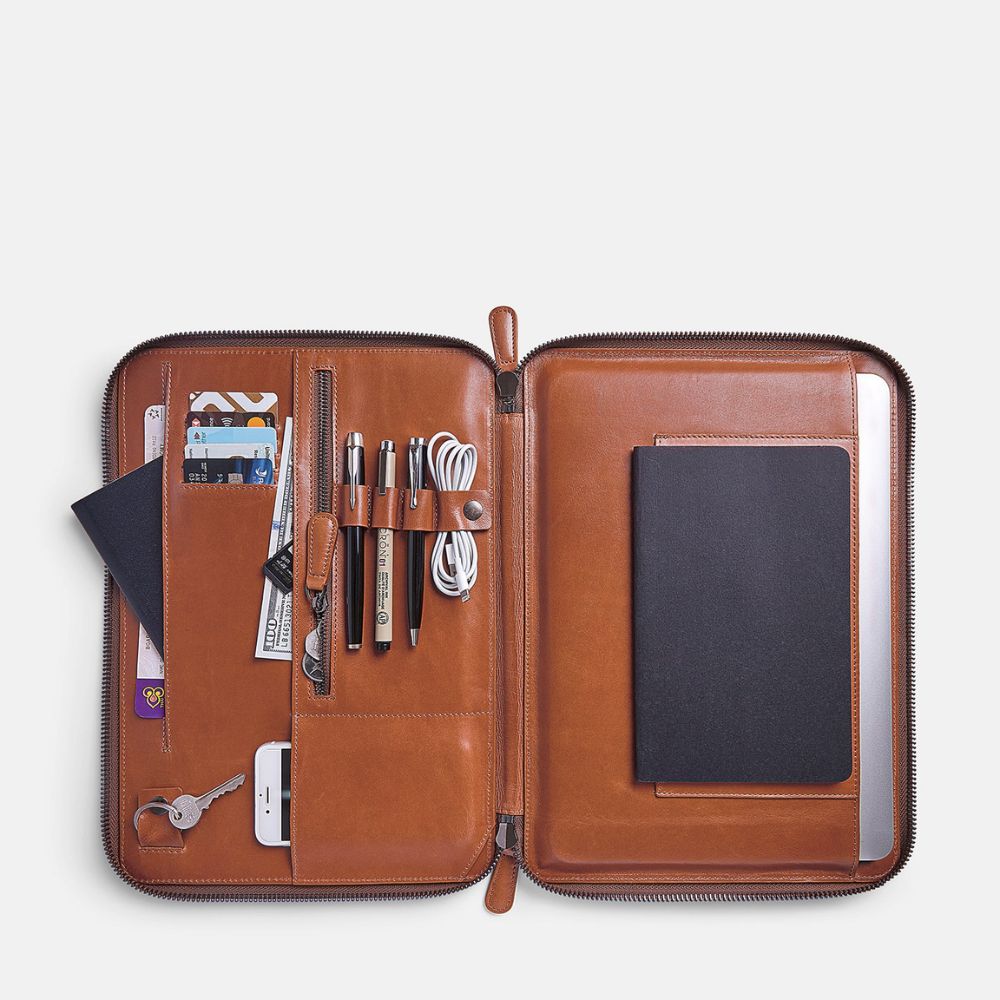 Caramel leather organizer with various items on a light gray background