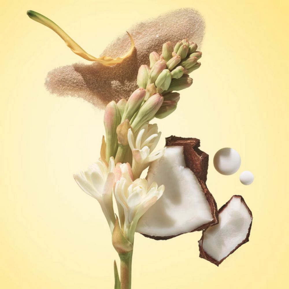 Composition on a yellow background featuring a sprig of white tuberose flowers and buds, pieces of coconut, a pile of light brown sand or granules, and two white drops.

- These are key ingredients used in SOL DE JANEIRO Rio Radiance™ SPF 50 Body Lotion