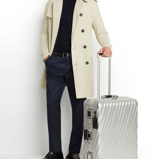 Person holding a silver suitcase against a white background
