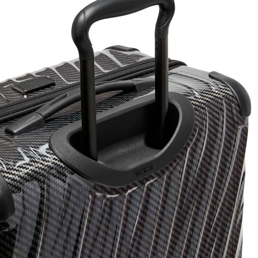 Close-up of a black suitcase handle on a textured surface