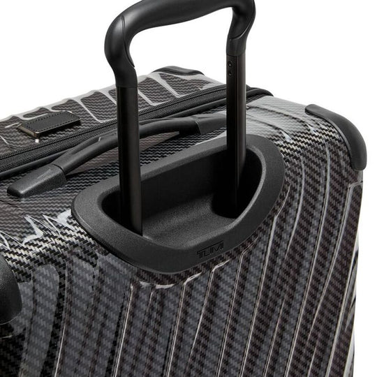 Close-up of a black suitcase handle on a textured surface