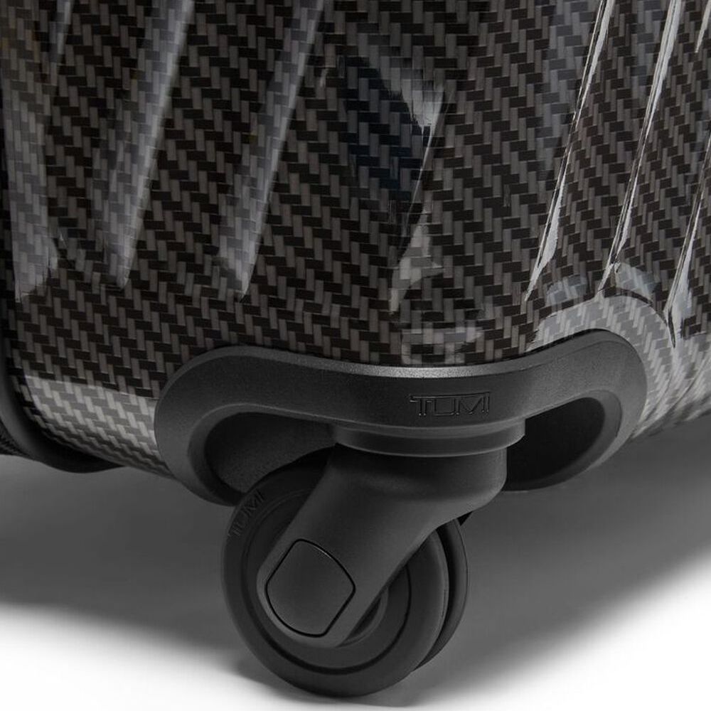 Close-up of a suitcase with a textured surface and black wheel on a light background