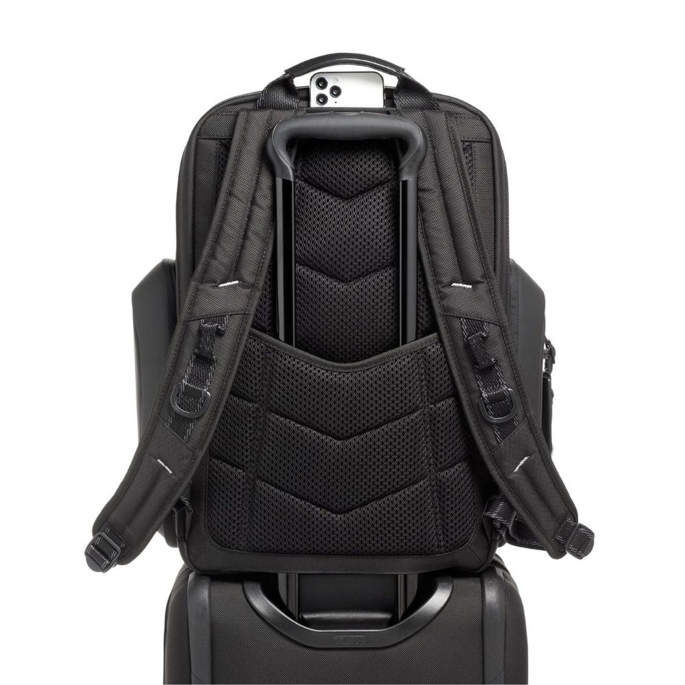 Black backpack attached to a suitcase on a white background
