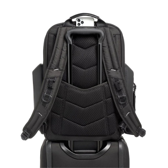 Black backpack attached to a suitcase on a white background