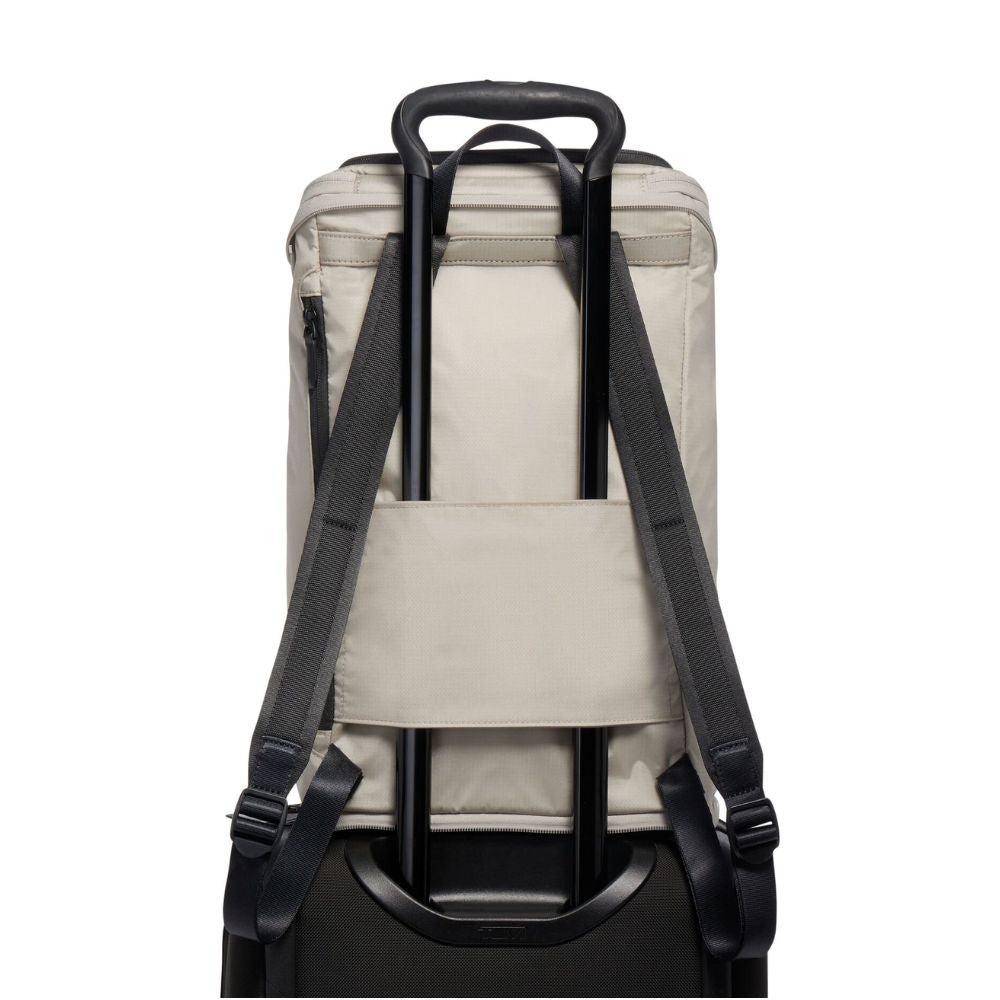 Back view of a beige backpack with black straps on a white background