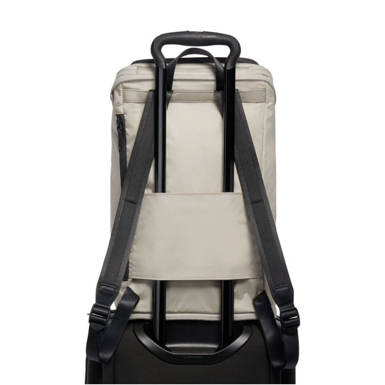 Back view of a beige backpack with black straps on a white background