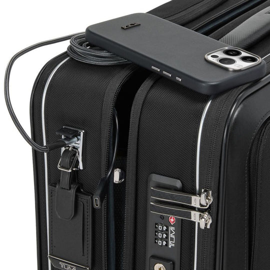 Close up of the combination lock on a Black briefcase with a phone on its top being charged via the USB charging port on the briefcase