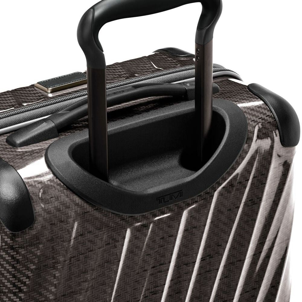 Close-up of a black suitcase handle on a textured surface