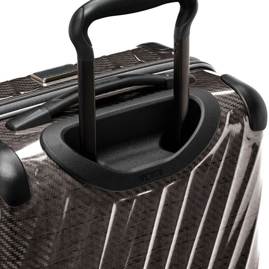 Close-up of a black suitcase handle on a textured surface
