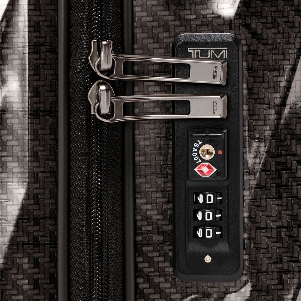 Close-up of a Tumi suitcase with a combination lock on a textured surface.