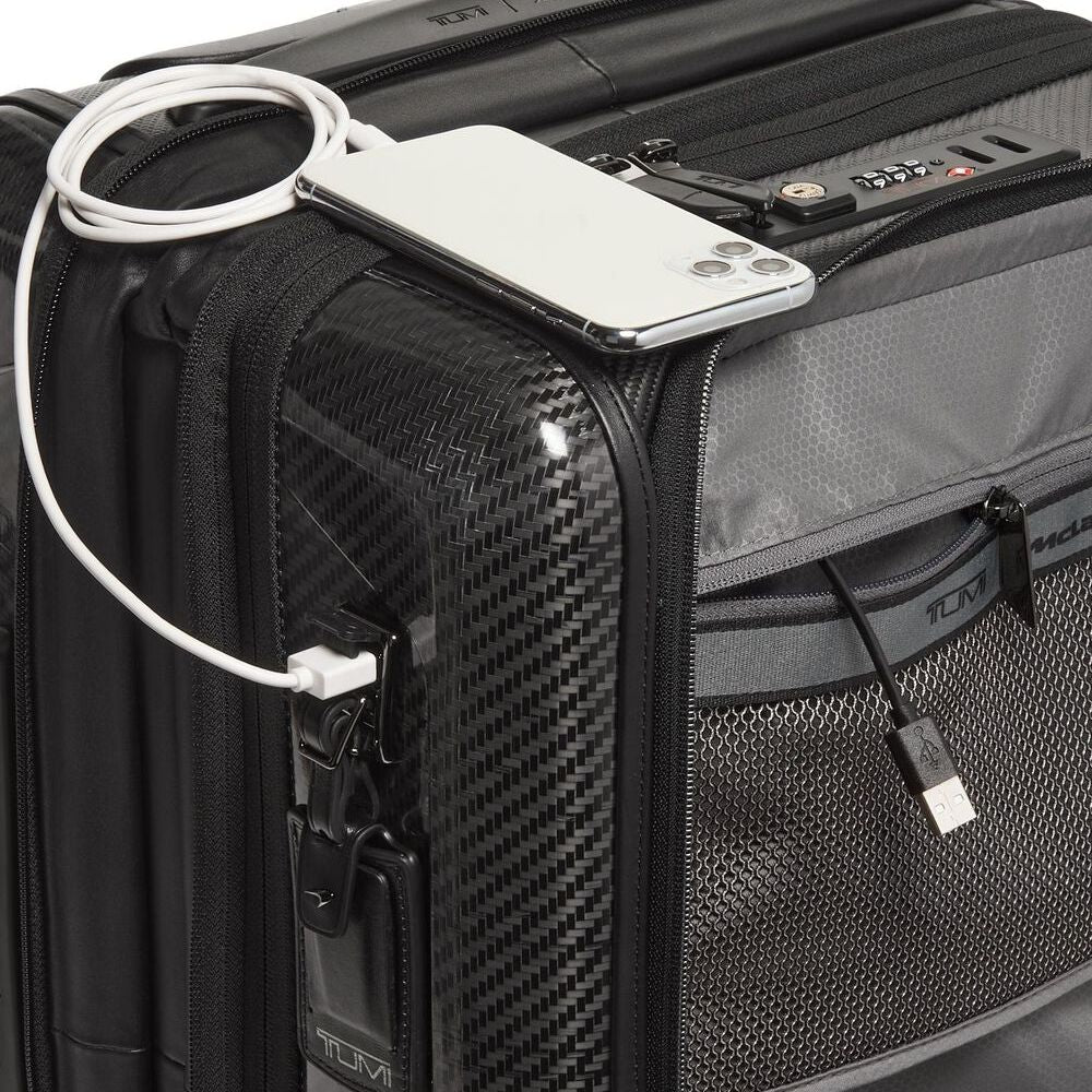 Black suitcase with a phone and cable attached, featuring TUMI branding.