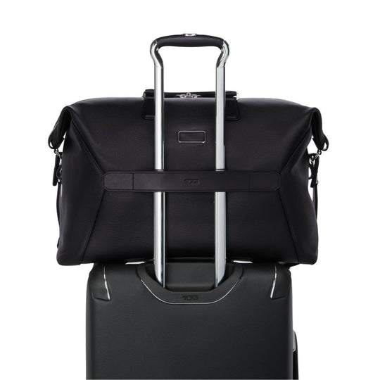 Black suitcase with a matching roll-top bag on a white background
