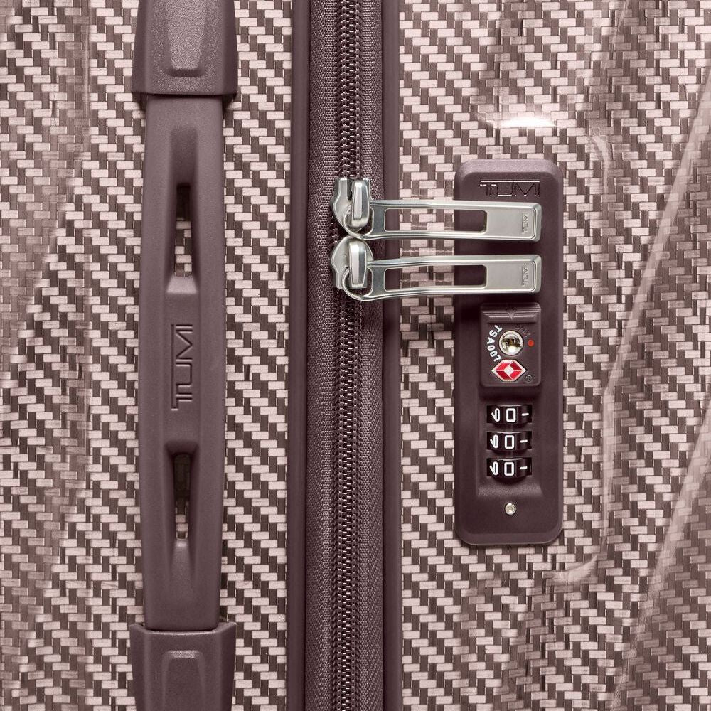 Close-up of a textured suitcase with a zipper and combination lock, featuring the Tumi brand.