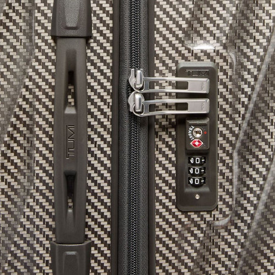 Close-up of a textured suitcase with a zipper and combination lock.