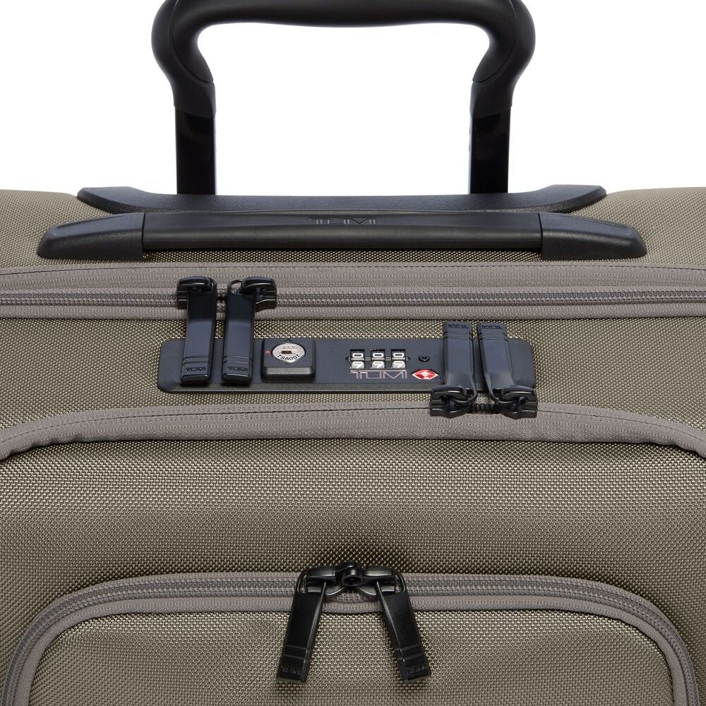 Close-up of a beige suitcase with a black handle and security lock on a white background