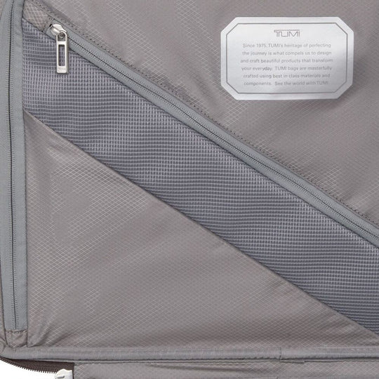 Gray suitcase with a TUMI label on a gray background