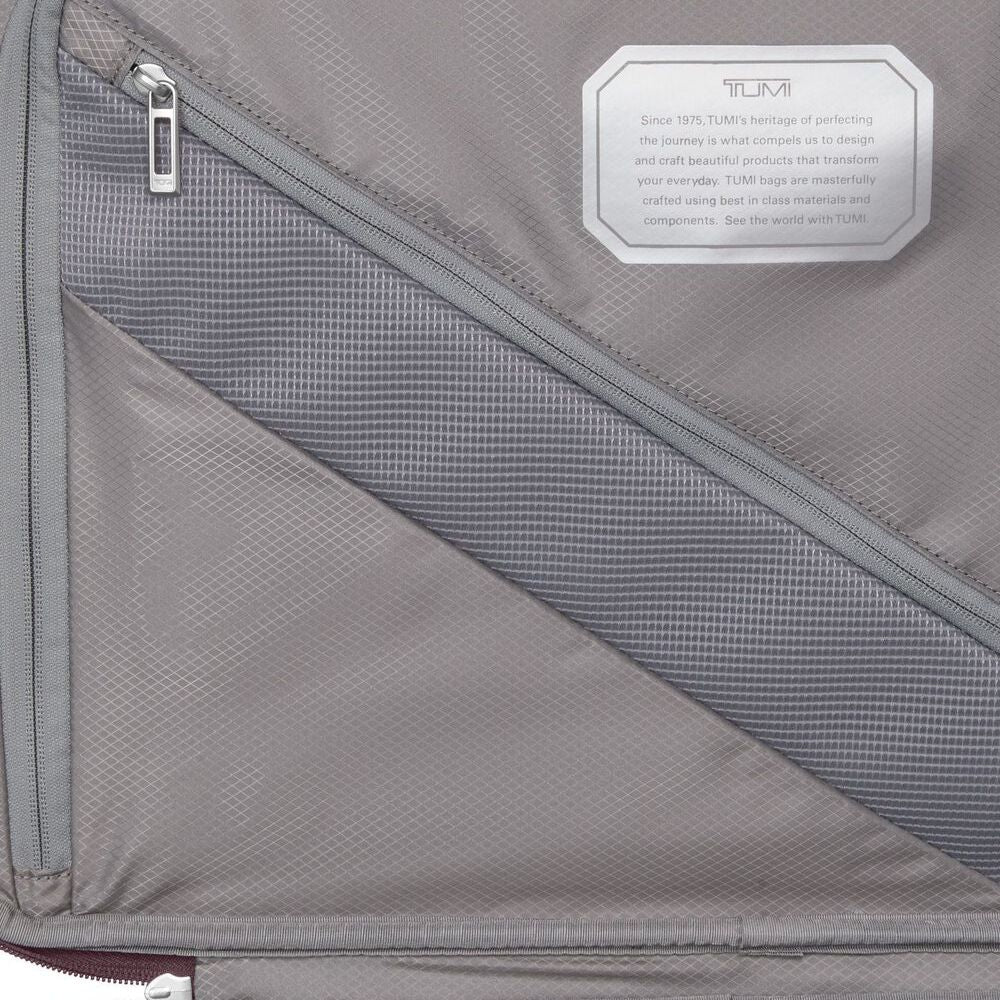 Gray suitcase with a TUMI label on a gray background