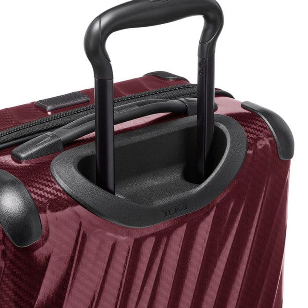 Close-up of a red suitcase with black handle and wheels on a white background