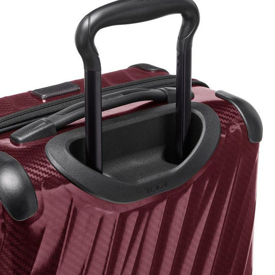 Close-up of a red suitcase with black handle and wheels on a white background